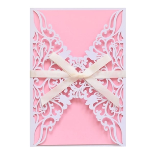 Detail of laser-cut hollow lace wedding invitation with a pink insert and silk ribbon bow