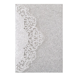 Macro detail of laser-cut lace pattern on silver glitter paper wedding invitation card
