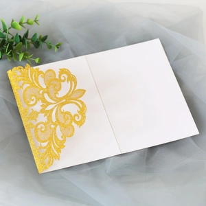Intricate laser-cut gold glitter vine pattern on celebratory invitation with white insert