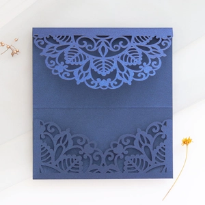 Macro view of laser-cut mandala floral patterns on navy blue pearlized wedding invitations
