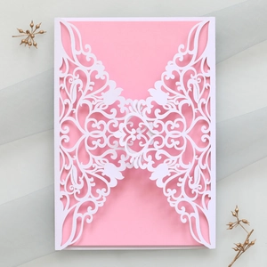 Detail of laser-cut hollow wedding invitation with white vine pattern and pink inner card