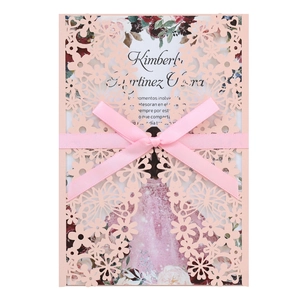 Macro detail of laser-cut butterfly invitation with pink ribbon and rose card