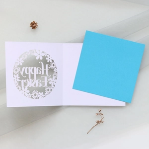 Detail of laser-cut Happy Easter card with floral patterns on blue paper background