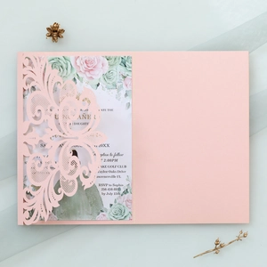Detail of pink laser-cut invitation with floral inner card on an elegant background