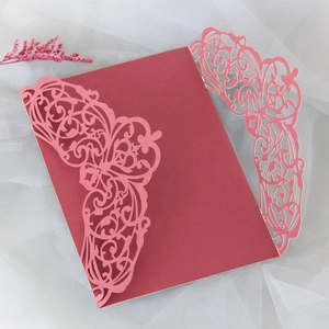 Detailed laser-cut wedding invitation cover in burgundy and pink with lace patterns