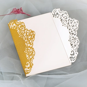 Détail d'invitation de mariage découpée au laser avec paillettes dorées et motif évidé