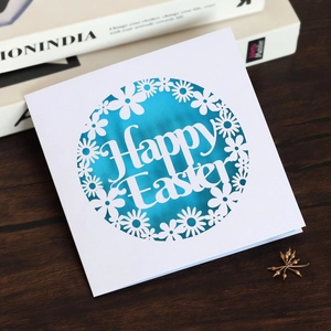 Detailed laser-cut Happy Easter card with white daisy patterns over a blue backdrop