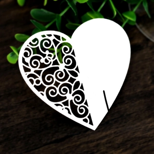 Detailed laser cut heart-shaped place card with elegant lace patterns on wood background