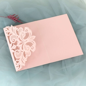Detailed laser-cut vine patterns on a pale pink lace wedding invitation cover