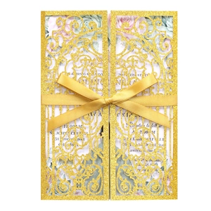 Intricate laser-cut gold glitter wedding invitation with floral insert and gold ribbon