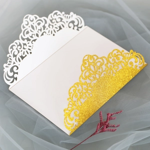 Détail d'invitation de mariage découpée au laser avec motif floral doré pailleté
