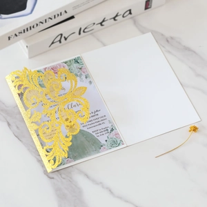 Detail of glitter gold laser-cut lace wedding invitation with floral printed insert