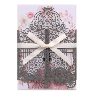 Detail showing laser-cut silver glitter invitation with a white ribbon and floral insert