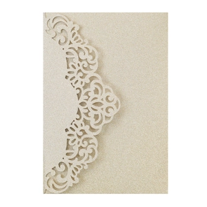 Macro shot of laser-cut gold glitter paper invitation with floral lace patterns