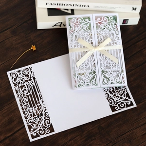 Détail d'invitation de mariage découpée au laser avec motifs baroques et nœud en ruban crème