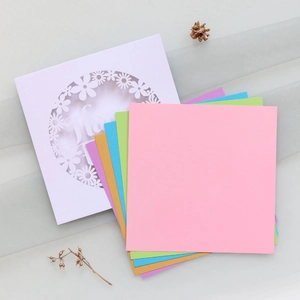 Macro shot of colorful pastel party invitations with laser-cut floral patterns and Happy text