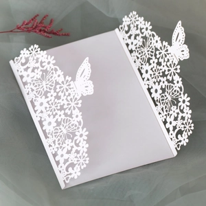 Detail of white laser-cut wedding invitation featuring intricate butterfly and floral patterns
