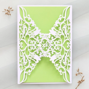 Detail of laser-cut floral invitation with green insert on grey gauze backdrop