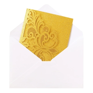 Close-up of laser-cut gold glitter invitation with intricate floral lace and white envelope