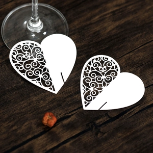 Macro view of white heart laser-cut paper cards on a wooden table for wedding decor