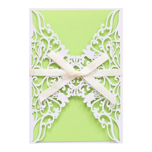 Detail of laser-cut floral wedding invitation with green inner card and cream ribbon bow