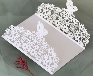 Detailed laser-cut white invitation cover with elegant hollow floral and butterfly patterns