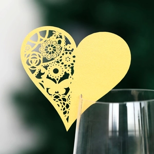 Yellow laser-cut heart place card with floral patterns on glass rim for weddings