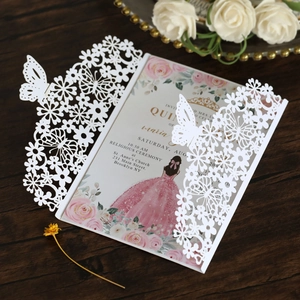 Detail of laser-cut butterfly invitation cover with pink floral insert on wood background