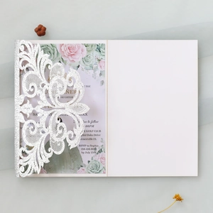 Macro shot of silver glitter laser-cut lace invitation featuring pink rose floral design