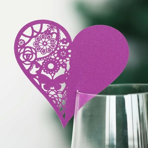 Detail of purple laser-cut heart place card with floral hollow pattern on wine glass