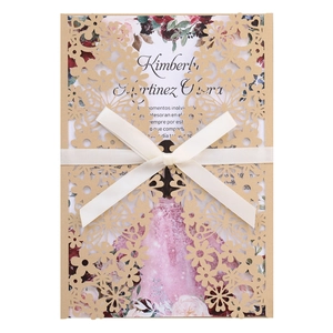 Detail of laser-cut gold floral invitation cover with cream ribbon and card insert