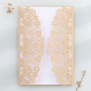 Macro view of gold laser-cut wedding invitation featuring butterfly and floral patterns