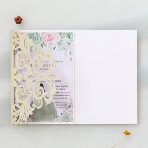 Macro detail of laser-cut gold glitter invitation cover with floral printed inner card