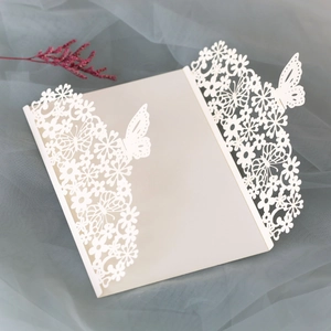 Detail of white laser-cut butterfly invitation cover with elegant floral hollow patterns