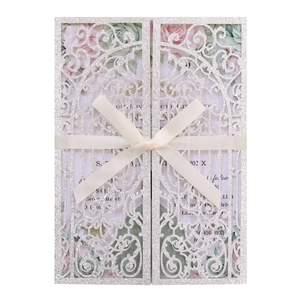 Close-up of laser-cut silver glitter wedding invitation with cream silk bow detail