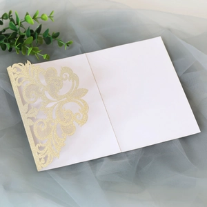 Close-up of laser-cut glitter gold lace invitation with intricate hollow floral patterns