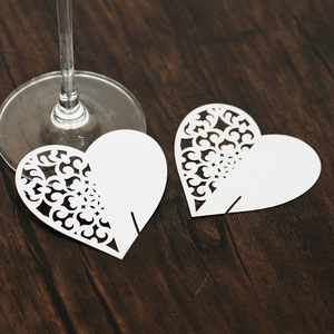 Detailed laser-cut heart paper place card for wine glasses on dark wood table