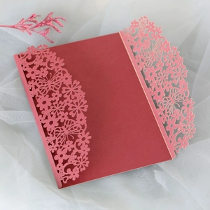 Macro view of laser-cut burgundy and pink wedding invitation with butterfly and floral patterns