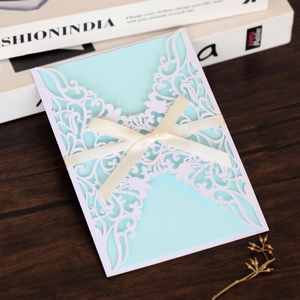 Intricate laser-cut butterfly invitation with cream ribbon on light blue cardstock