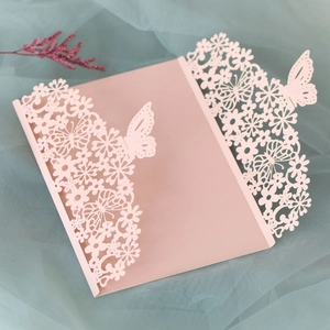 Detail of pink laser-cut wedding invitation featuring intricate butterfly and floral patterns
