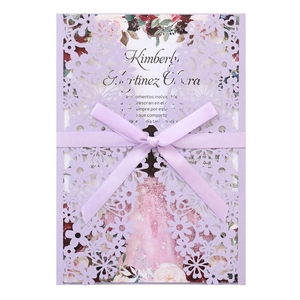 Intricate laser-cut lavender invitation with a ribbon bow and floral inner page