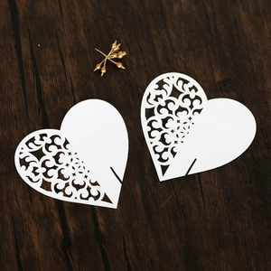 Detail of white laser-cut heart place card with intricate patterns on a wood background