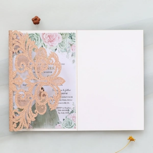 Close-up of laser-cut rose gold glitter wedding invitation with floral insert card