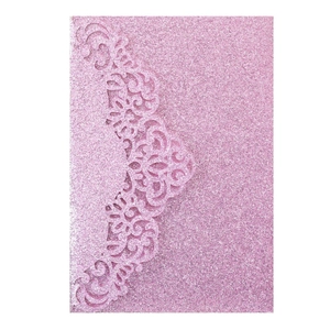 Detail of pink glitter laser-cut invitation card with intricate floral lace texture