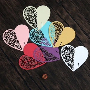 Macro detail of laser-cut heart place cards in various colors on dark wood background