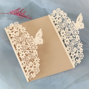 Detailed laser-cut butterfly and floral patterns on cream trifold wedding invitation covers
