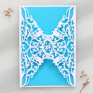 Detail of white laser-cut floral invitation cover with blue inner card insert