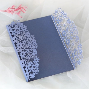 Detail of laser-cut butterfly floral patterns on navy blue pearlescent wedding invitation