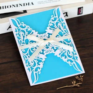 Close-up of laser-cut butterfly invitation with blue insert and white silk ribbon bow