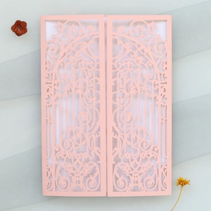 Vue macro d'un faire-part de mariage rose clair découpé au laser avec motifs floraux